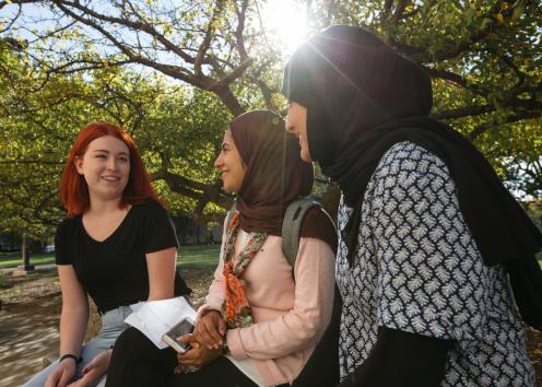 Three students are sitting and chatting